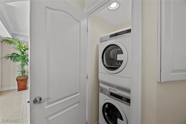 laundry area featuring tile patterned flooring, laundry area, and stacked washing maching and dryer