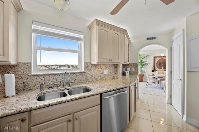 kitchen featuring a ceiling fan, a sink, stainless steel dishwasher, arched walkways, and light tile patterned floors