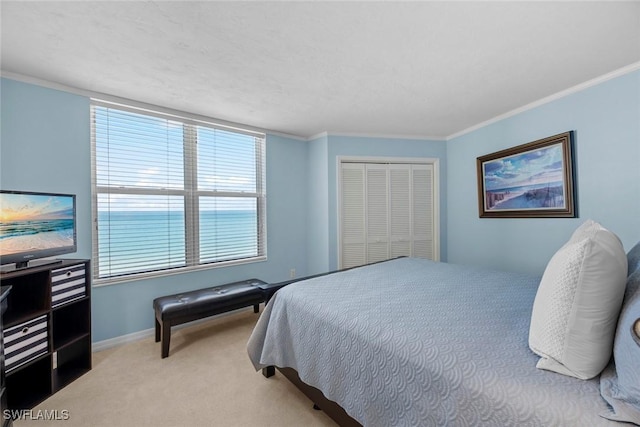 carpeted bedroom with a closet, baseboards, and ornamental molding