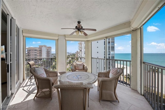 sunroom with a water view and ceiling fan