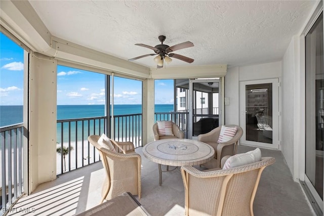 sunroom featuring a ceiling fan and a water view