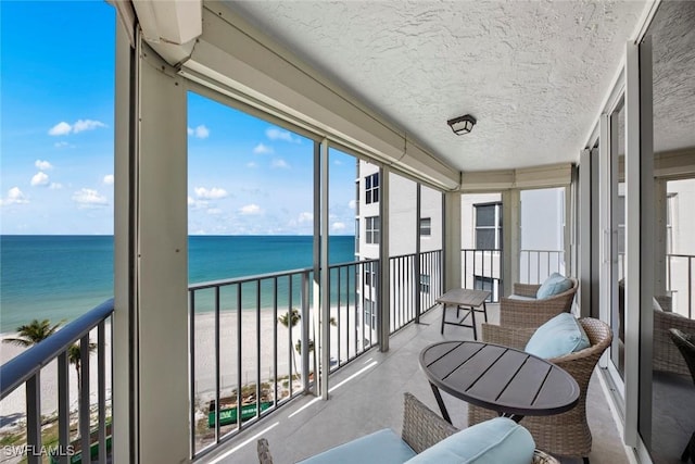 sunroom / solarium featuring a beach view and a water view