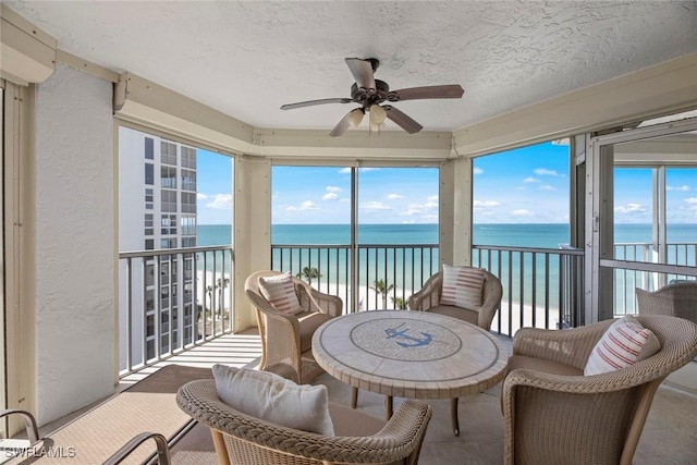 sunroom featuring plenty of natural light, a ceiling fan, and a water view