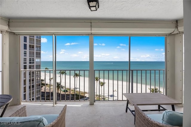 sunroom / solarium with a wealth of natural light, a view of the beach, and a water view