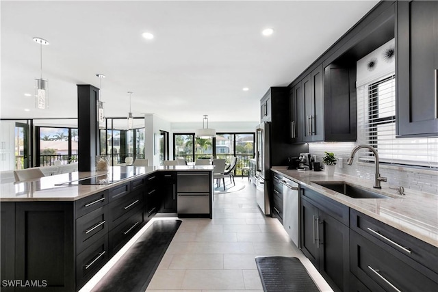 kitchen featuring a sink, light stone counters, tasteful backsplash, stainless steel appliances, and dark cabinets