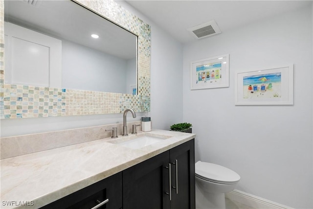 bathroom featuring visible vents, baseboards, toilet, recessed lighting, and vanity