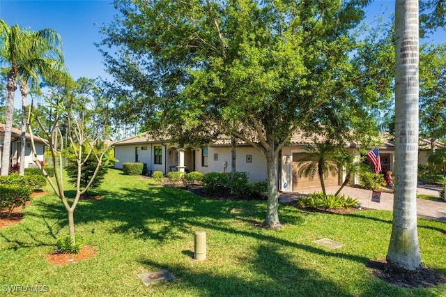 view of front facade featuring a garage, stucco siding, driveway, and a front yard