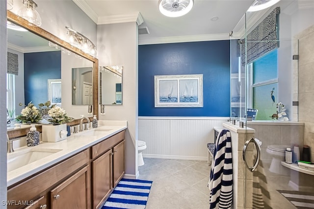 full bathroom featuring a tile shower, ornamental molding, a sink, wainscoting, and toilet