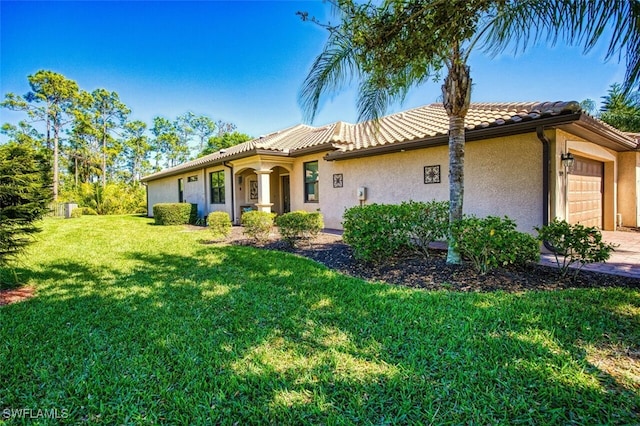 mediterranean / spanish home featuring stucco siding, an attached garage, a front lawn, and a tiled roof