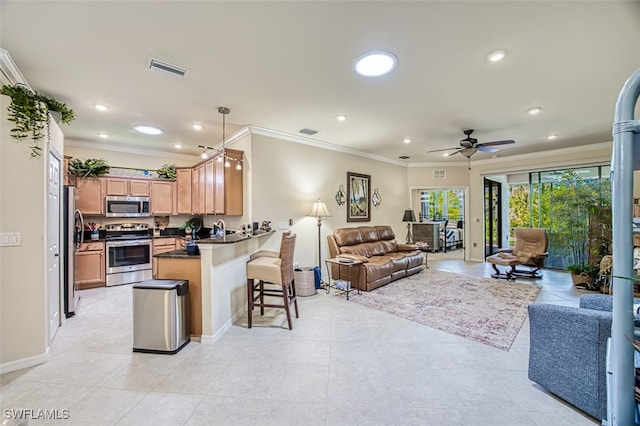 kitchen featuring dark countertops, open floor plan, appliances with stainless steel finishes, and a kitchen breakfast bar