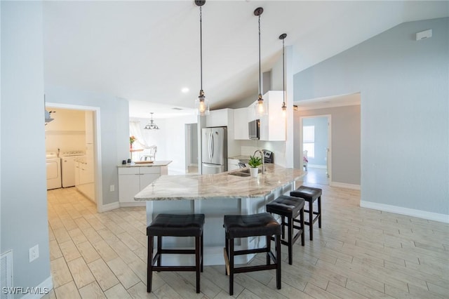 kitchen featuring washer and dryer, a peninsula, lofted ceiling, and appliances with stainless steel finishes