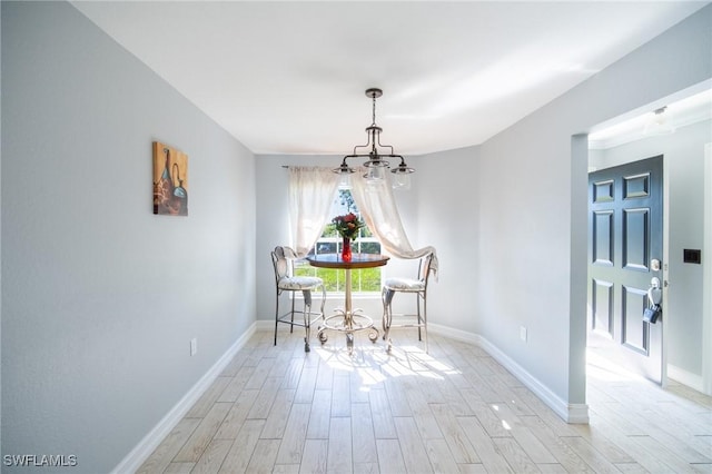 dining space featuring light wood-type flooring, baseboards, and a chandelier