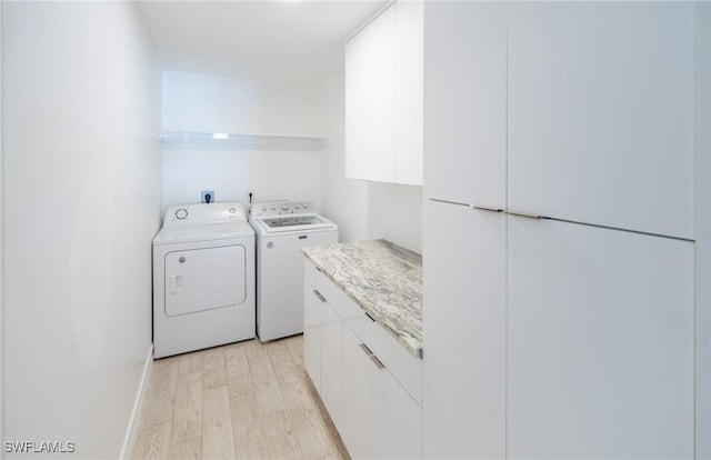 laundry area with cabinet space, light wood-style flooring, and washing machine and dryer