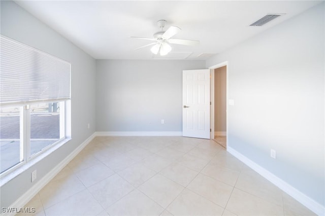 empty room featuring light tile patterned floors, a ceiling fan, visible vents, and baseboards