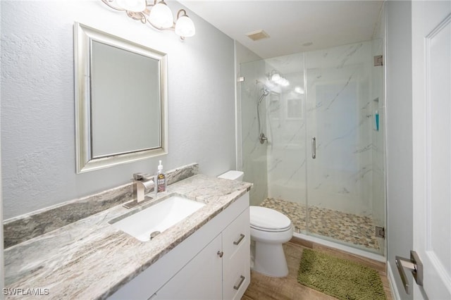 full bath with a marble finish shower, visible vents, toilet, and vanity