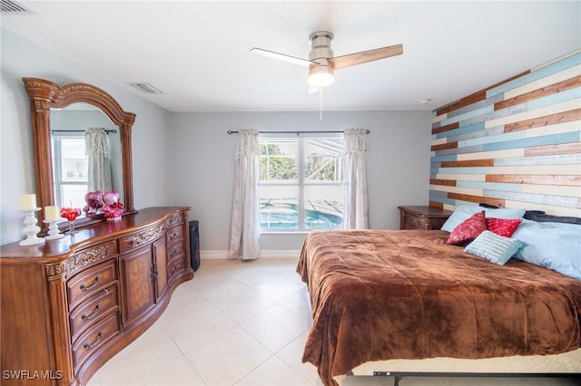 bedroom with visible vents, ceiling fan, an accent wall, and baseboards