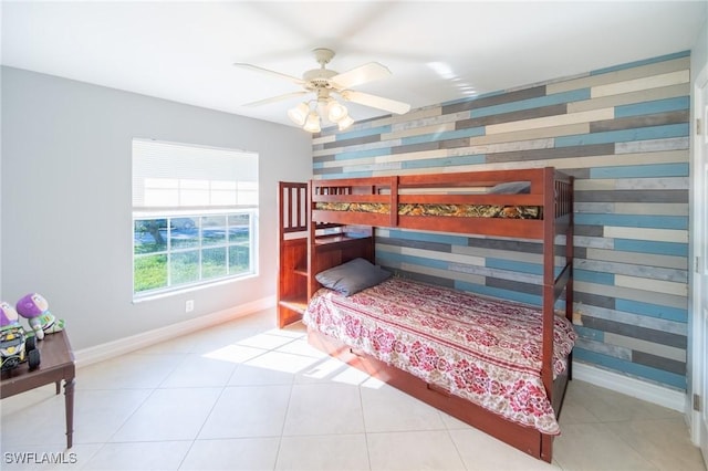 bedroom with tile patterned floors, baseboards, ceiling fan, and an accent wall