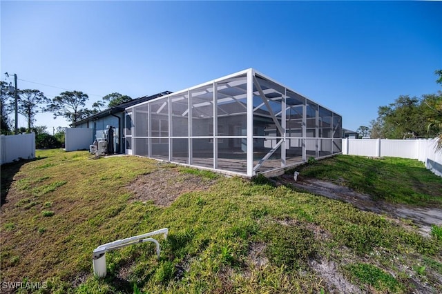 back of house with a lanai, a yard, and a fenced backyard