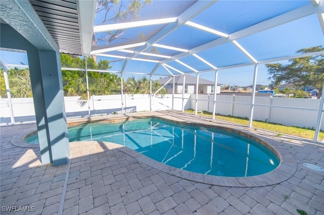 view of pool featuring glass enclosure, a patio, a fenced backyard, and a fenced in pool