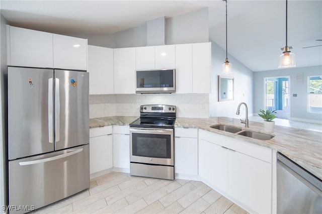 kitchen featuring light stone countertops, a sink, decorative backsplash, stainless steel appliances, and white cabinetry