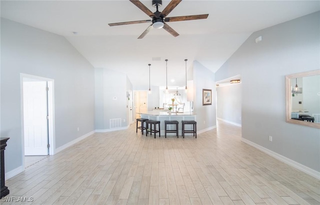 unfurnished living room featuring baseboards, visible vents, high vaulted ceiling, light wood finished floors, and ceiling fan