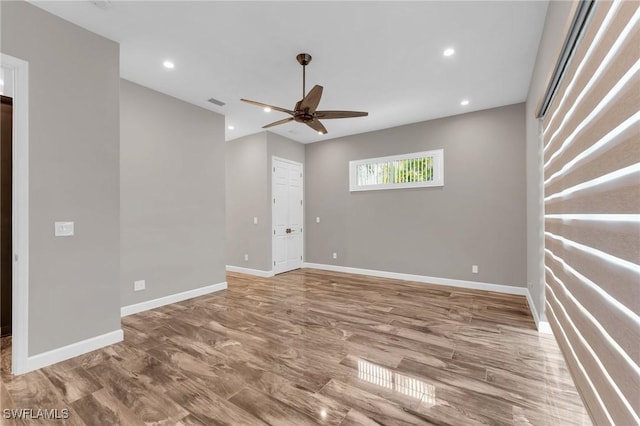 spare room with wood finished floors, a ceiling fan, and baseboards