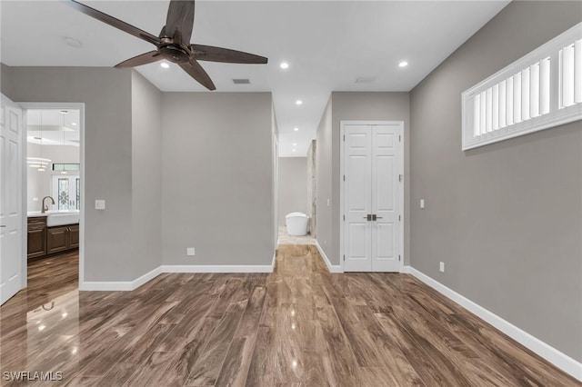 unfurnished bedroom with recessed lighting, ensuite bathroom, baseboards, and wood finished floors