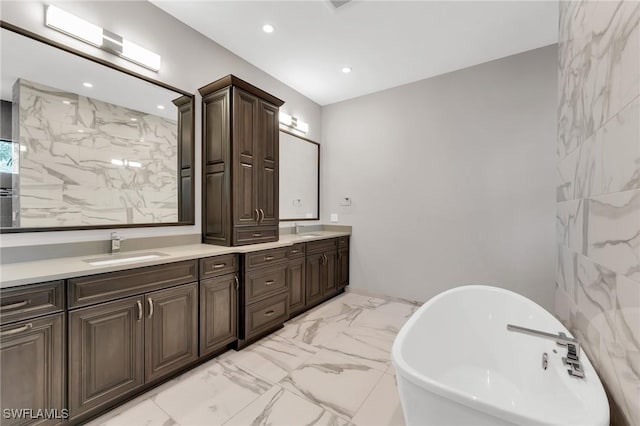 bathroom with double vanity, a soaking tub, marble finish floor, and a sink