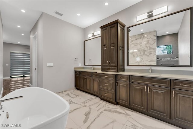 full bath with visible vents, double vanity, a freestanding bath, a sink, and marble finish floor