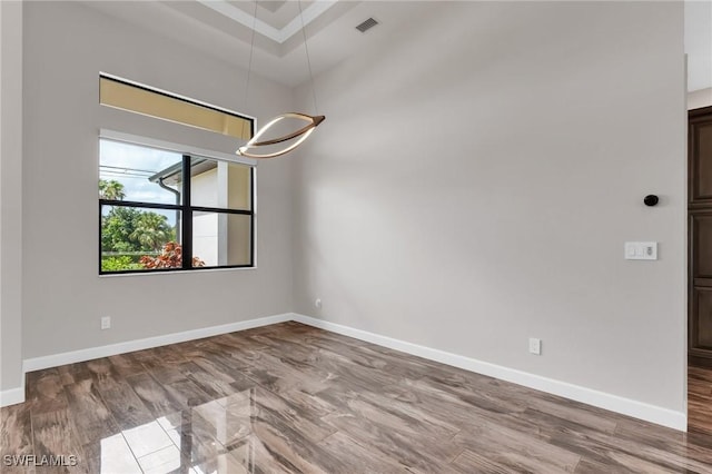 empty room featuring visible vents, baseboards, and wood finished floors