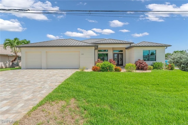 view of front facade with a front lawn, metal roof, decorative driveway, a garage, and a standing seam roof