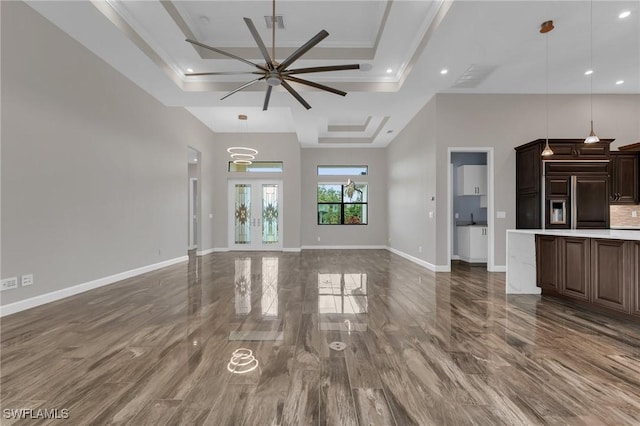 unfurnished living room featuring baseboards, a ceiling fan, crown molding, and a tray ceiling