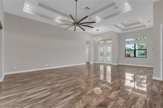 unfurnished living room with ceiling fan, baseboards, a tray ceiling, and ornamental molding