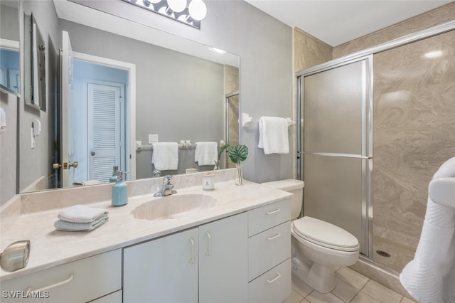 bathroom featuring tile patterned floors, toilet, a stall shower, and vanity