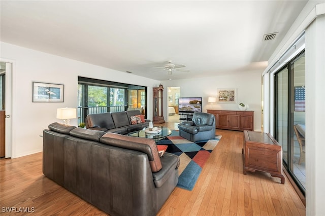 living room featuring visible vents, baseboards, a ceiling fan, and light wood finished floors