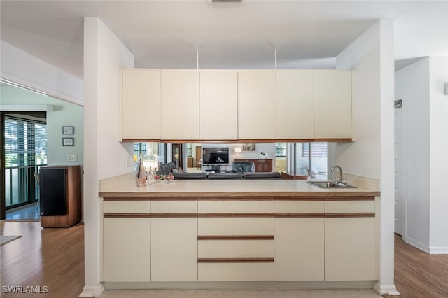 kitchen featuring a sink, cream cabinetry, light countertops, and light wood finished floors