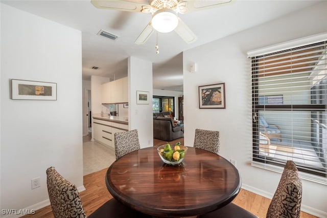 dining space featuring visible vents, baseboards, ceiling fan, and light wood-style flooring