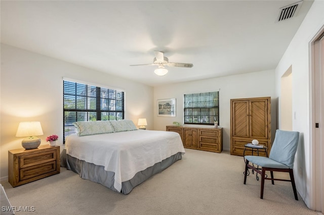 bedroom with ceiling fan, visible vents, and light carpet