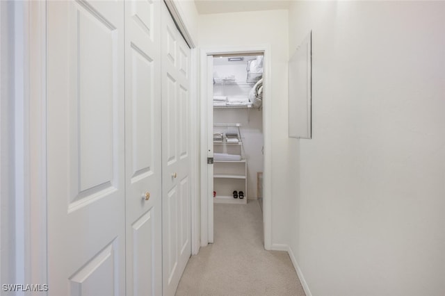 hallway with baseboards and light colored carpet