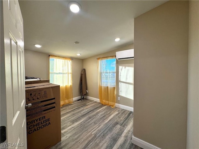 interior space featuring lofted ceiling, a healthy amount of sunlight, wood finished floors, and a wall mounted AC