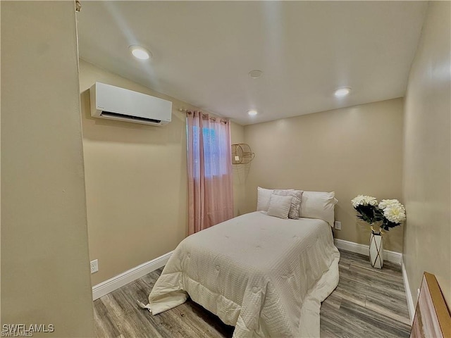 bedroom with recessed lighting, an AC wall unit, baseboards, and wood finished floors