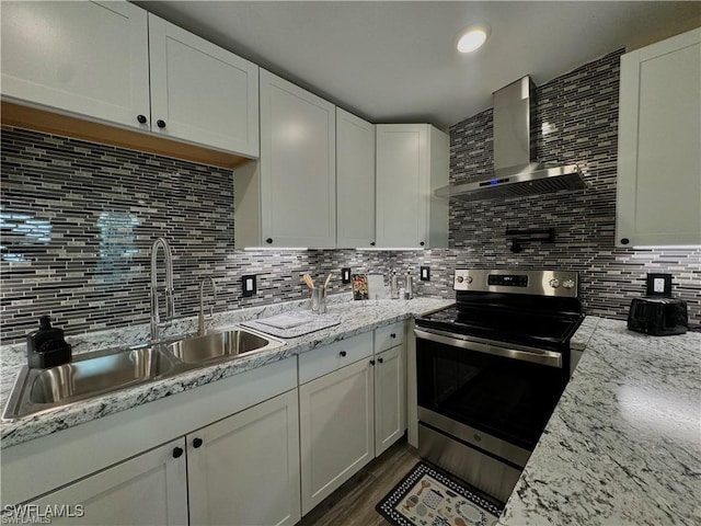 kitchen featuring a sink, tasteful backsplash, white cabinetry, wall chimney range hood, and stainless steel electric range oven