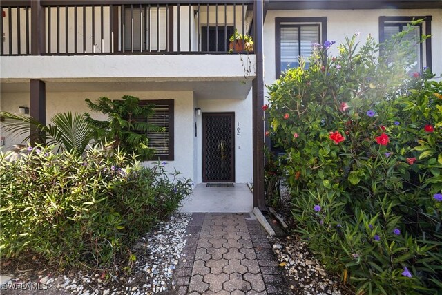doorway to property featuring stucco siding and a balcony