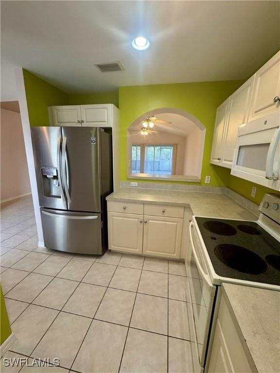 kitchen featuring white appliances, white cabinets, light tile patterned floors, and light countertops