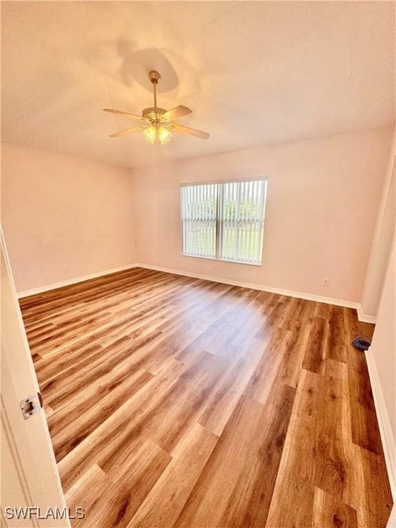 spare room featuring a ceiling fan, wood finished floors, and baseboards