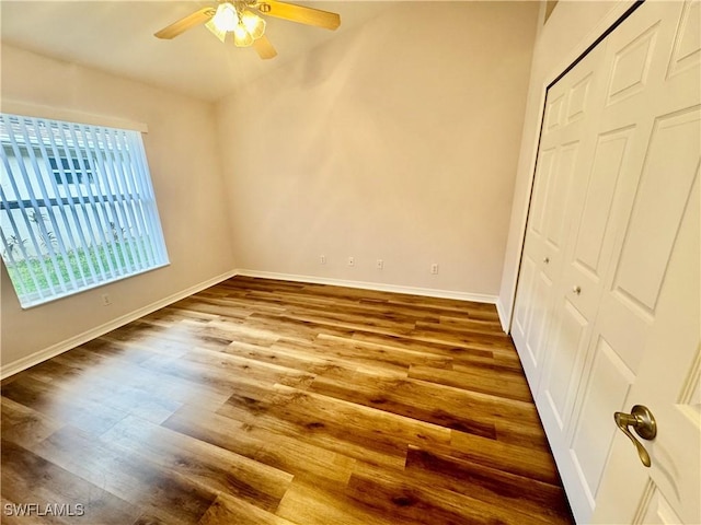 unfurnished bedroom featuring ceiling fan, a closet, baseboards, and wood finished floors