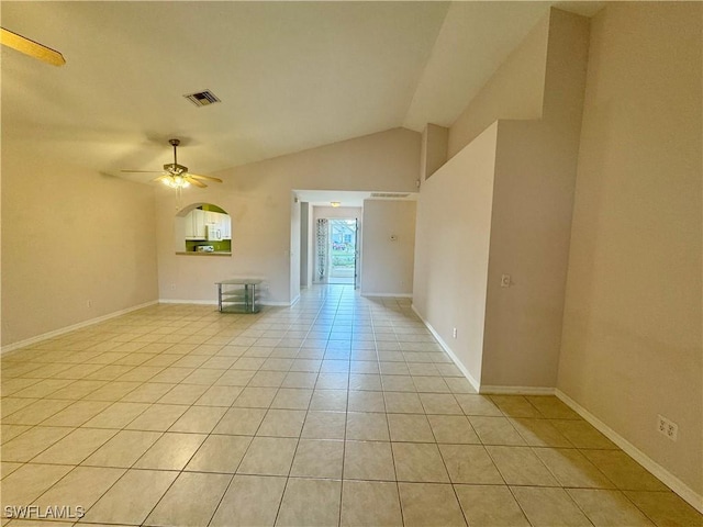 empty room with visible vents, baseboards, vaulted ceiling, light tile patterned floors, and a ceiling fan