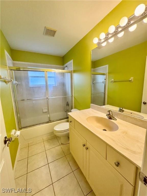 full bath with visible vents, toilet, combined bath / shower with glass door, tile patterned flooring, and vanity