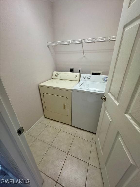 laundry area featuring light tile patterned floors, laundry area, washer and dryer, and baseboards