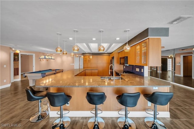 kitchen with visible vents, a peninsula, a sink, glass insert cabinets, and black microwave